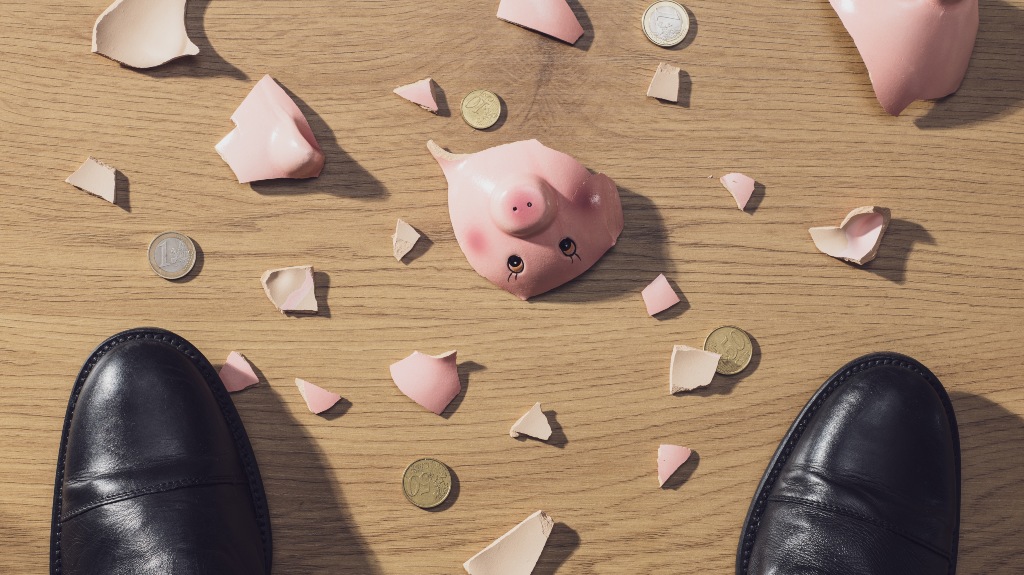 broken piggy bank and man's legs