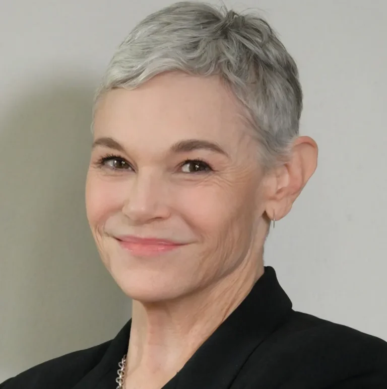 Professional headshot of a smiling middle-aged woman with short gray hair wearing a black blazer.